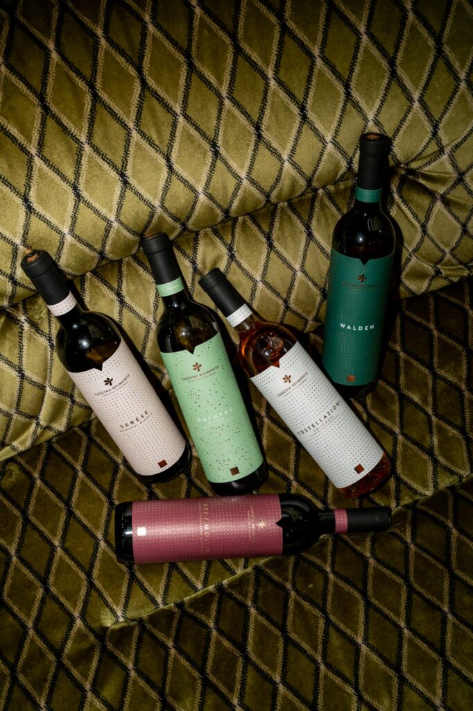 Collection of wine bottles displayed on a stylish carpeted sofa, showcasing elegant labels.